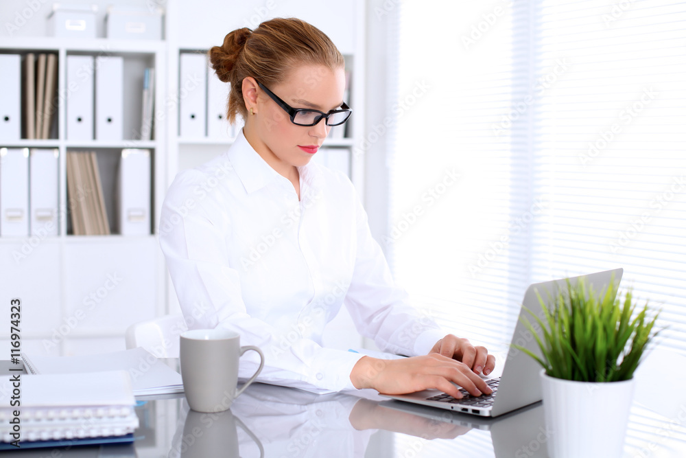 Business woman is typing on laptop computer. Bookkeeper or female financial inspector  making report, calculating or checking balance.