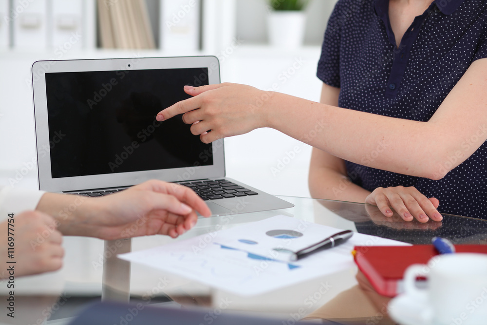 Group of business people at meeting discussing financial results. Women pointing into laptop computer monitor Group of business people at meeting discussing financial results. Women pointing into laptop computer monitor