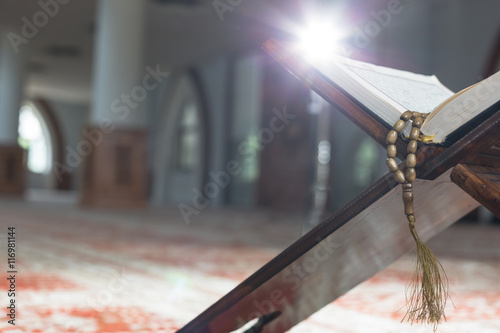 Holy Quran with beads over wooden background closeup. Small shal