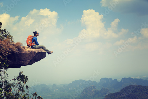 Fotografia successful woman backpacker sit on mountain peak cliff