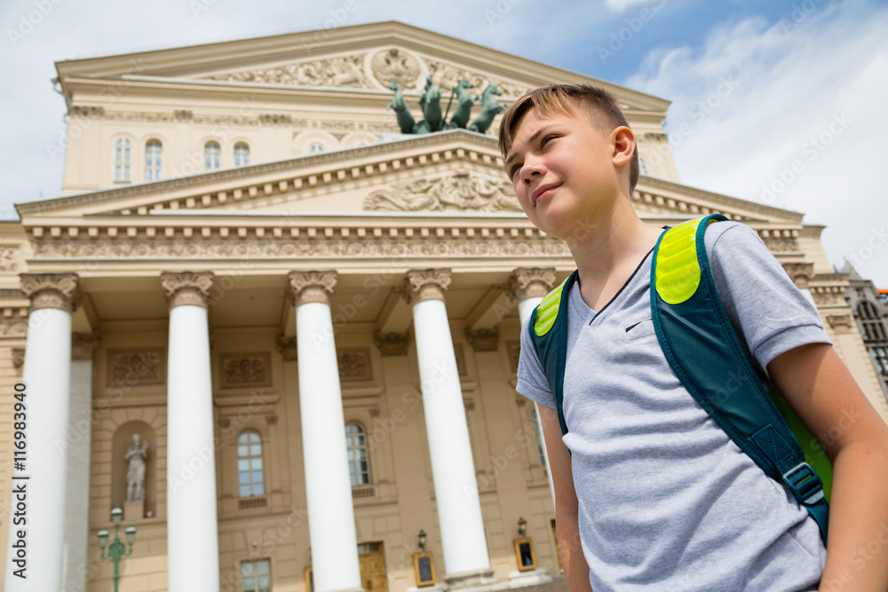 Boy stands in background of the Bolshoi Theatre