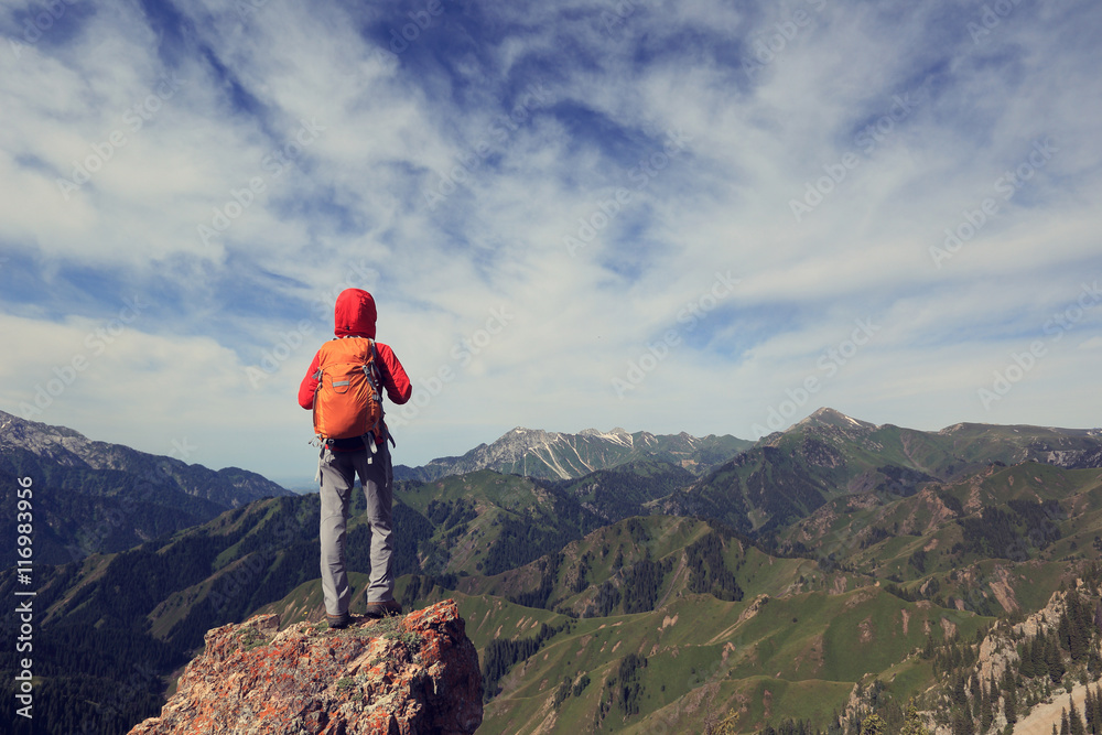successful woman backpacker hiking  on mountain peak cliff