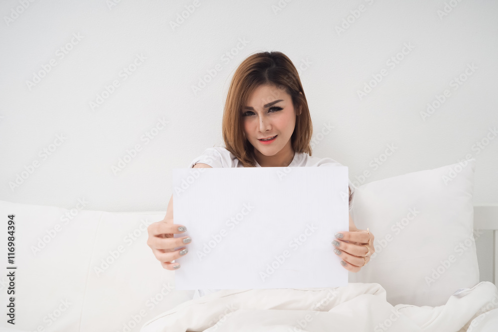 Asian woman sitting on white bed and holding blank paper. Asian woman sitting on white bed and holding blank paper.