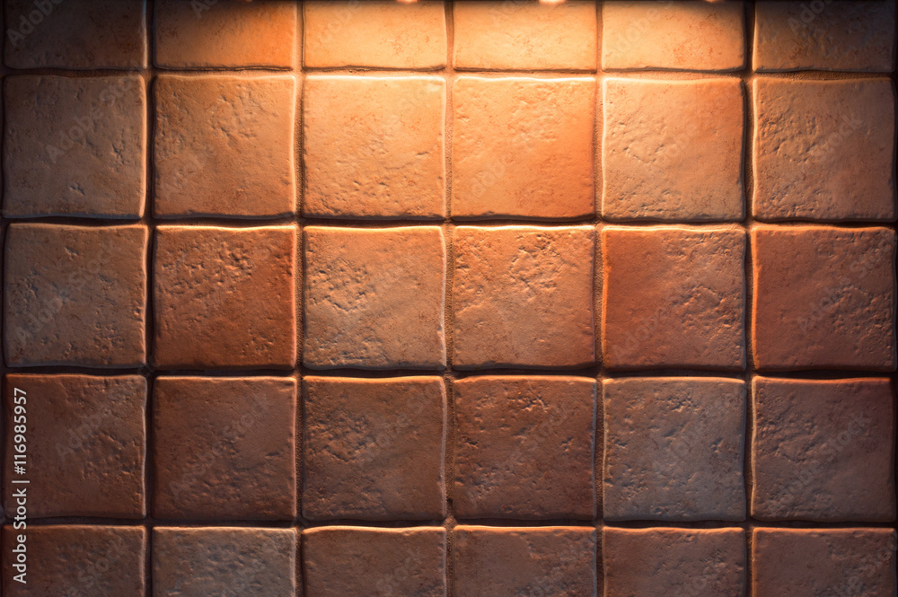 Naklejka premium Texture of fine ceramic tiles for kitchen wall illuminated from above. Close up tiled background.