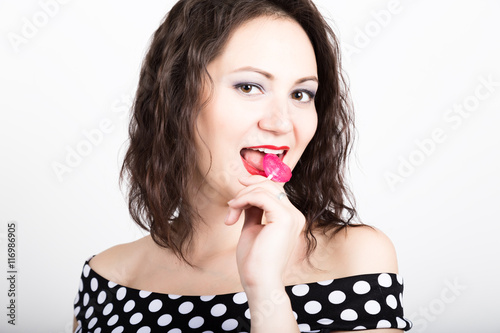 Portrait of happy beautiful young woman licking sweet candy and expressing different emotions. pretty woman with heart shaped lollipop