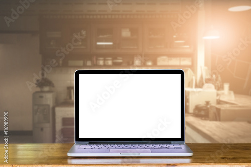 Front view blank laptop on wooden desk with kitchen room blur ba