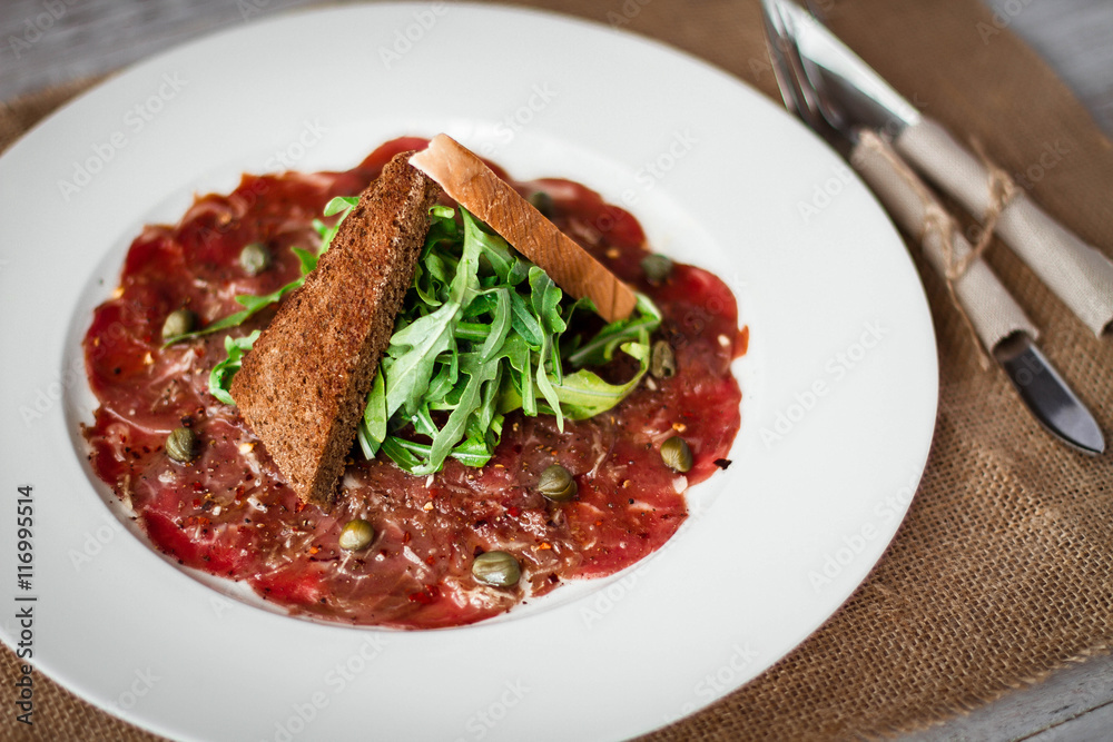 Fototapeta premium Meat carpaccio of beef on wood table