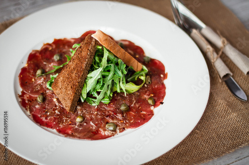 Meat carpaccio of beef on wood table