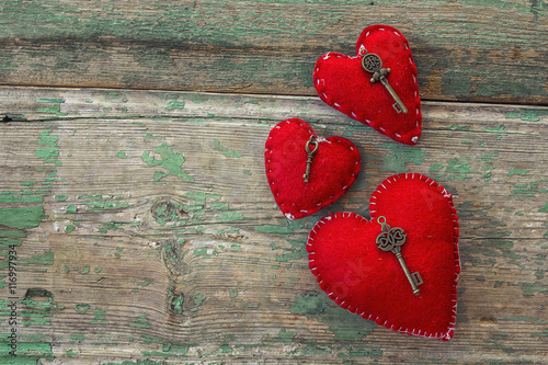 Red hearts with antique keys on old painted wooden boards.The me