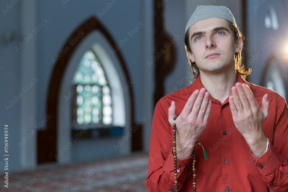 Young muslim man is praying in the mosque