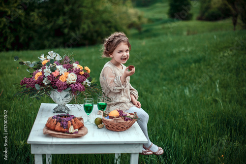 Little baby girl eats chocolate cake in nature at a picnic. The concept of a happy childhood