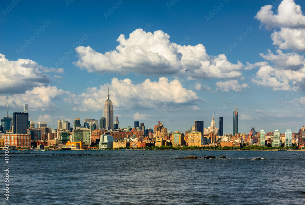 Naklejka premium Wieżowce Manhattan Midtown West i rzeka Hudson z przepływającymi chmurami. Pejzaż w letnie popołudnie w Nowym Jorku z widokiem na Midtown i West Village