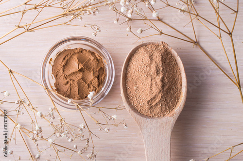 Cosmetic clay powder in a wooden spoon and clay in a jar on a wooden background. Healthy skin care.