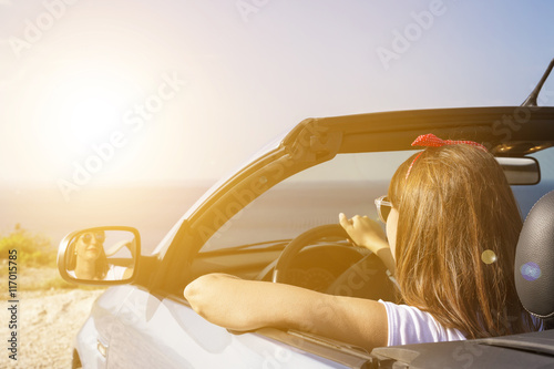 Young woman drive a car on the beach.