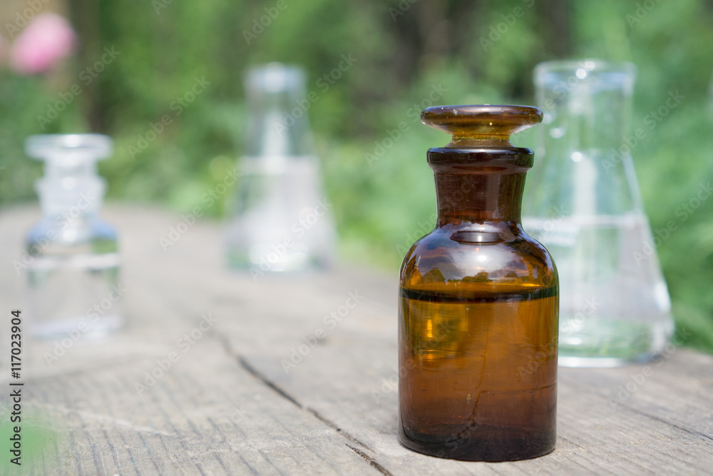 Liquid in chemical ware on a background of plants, fertilizers or pesticides in the garden. Liquid in chemical ware on a background of plants, fertilizers or pesticides in the garden.
