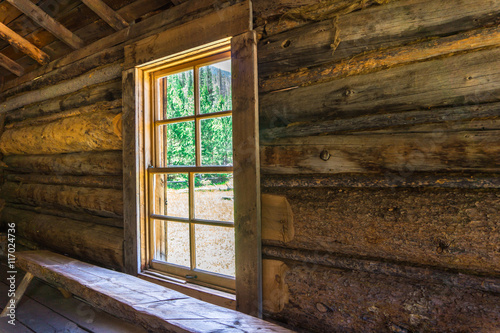window letting in the sun light in a log cabin
