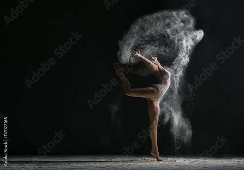 Fototapeta Naklejka Na Ścianę i Meble -  Concept. Flexible girl dancing in cloud of dust