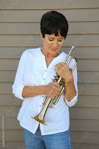 Photography Female jazz trumpet player holding her horn outside.