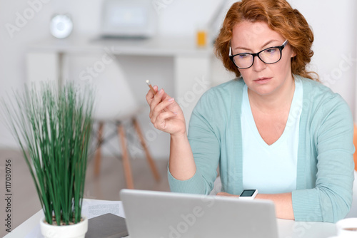Concentrated senior woman sitting at the table
