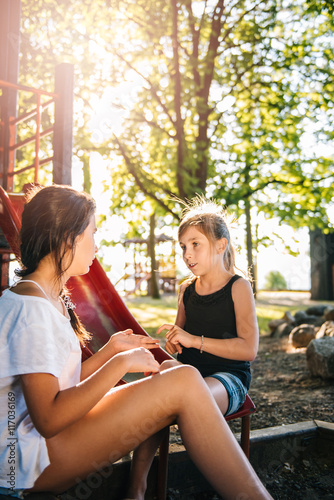 Two girls talking on a playground in summer