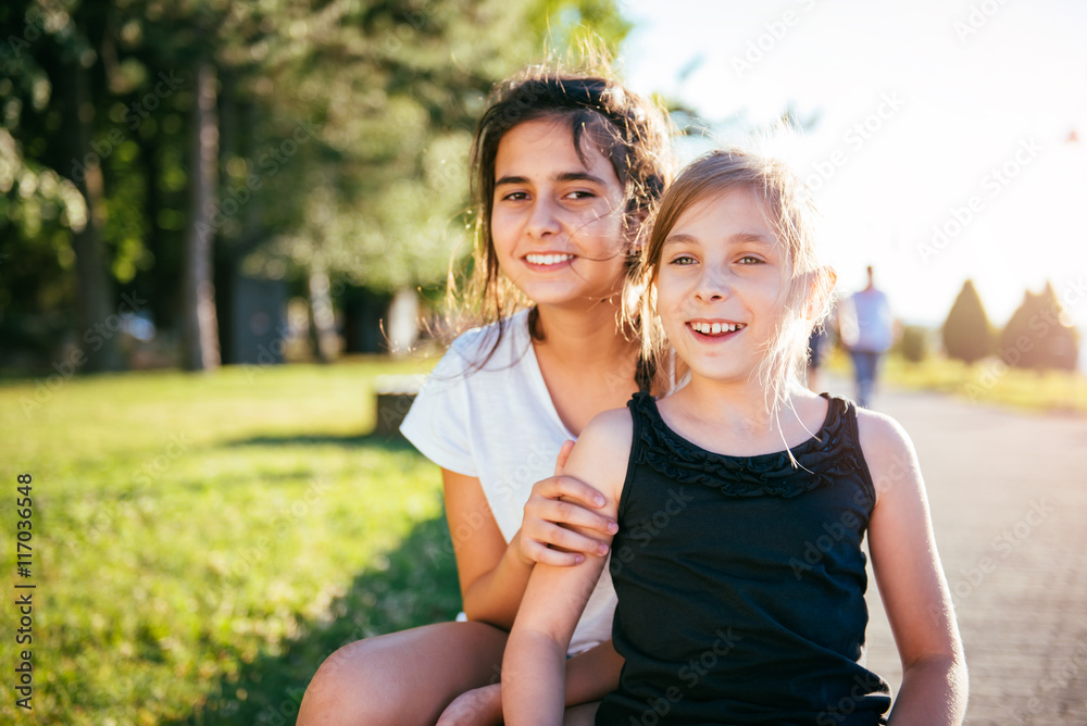 Obraz premium Two girls smiling together in a park