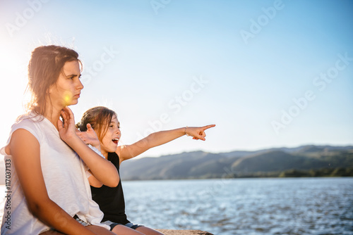 Two girls sitting on dock and pointing