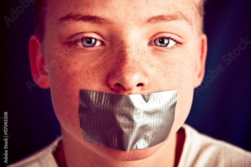 Young Teenage Boy with Duct Tape Covering Mouth photo