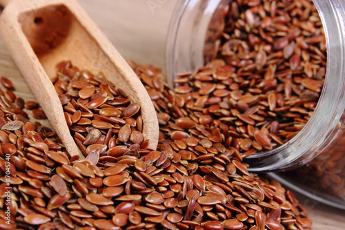 Linseed spilling out of jar on wooden background photo