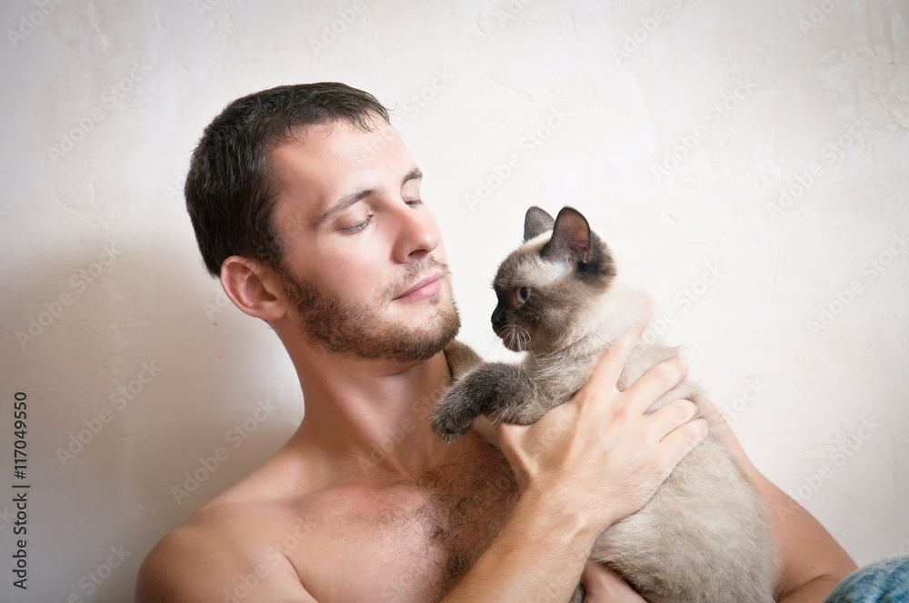 Portrait of a young attractive smiling man with cat in hands