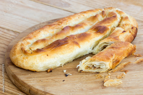 Cuadro en lienzo Sliced burek with meat on the wooden board. Rustic food.