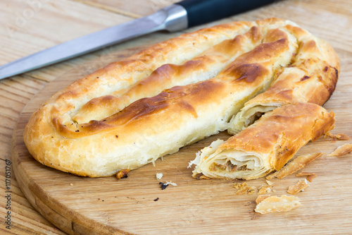 Sliced burek with meat on the wooden board. Rustic food. photo