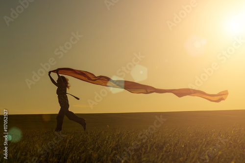 Young woman running on a rural road at sunset in summer field. Lifestyle freedom sports background. Happiness concept.