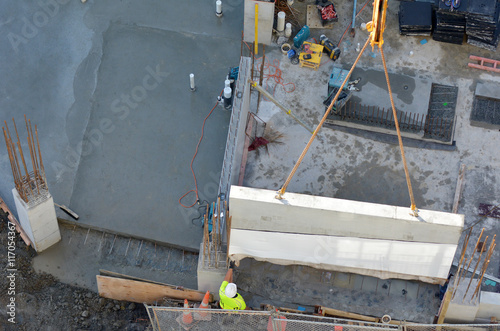 Construction workers guides a structural precast concrete into p