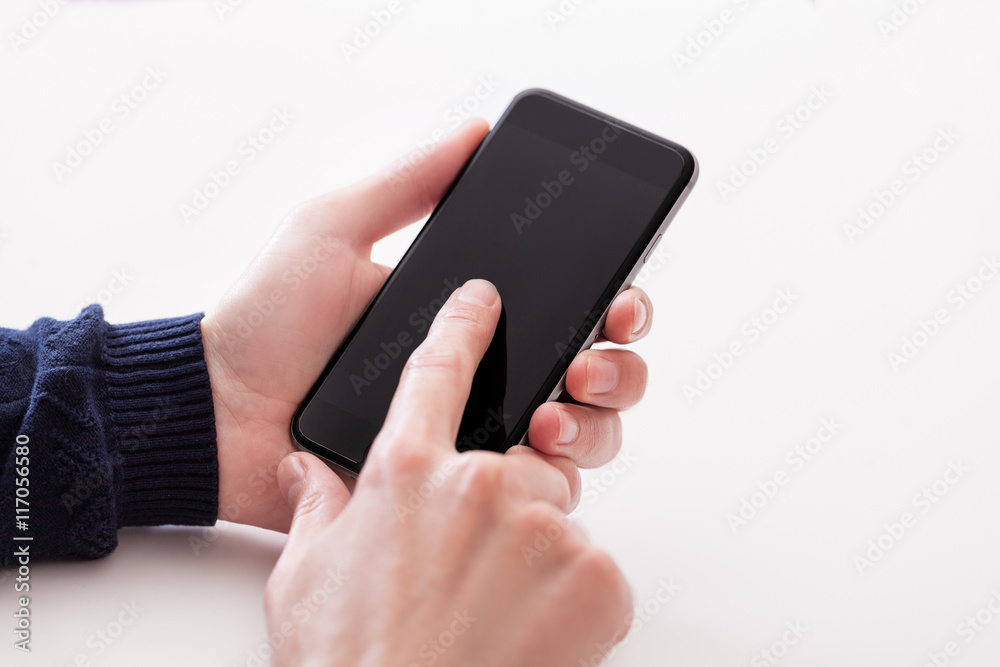 Hand holding smart mobile phone on wooden table and light blurre