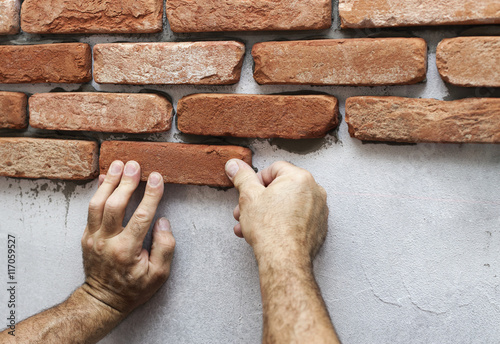 Fotografie Wall facing work with brick by professional bricklayer worker