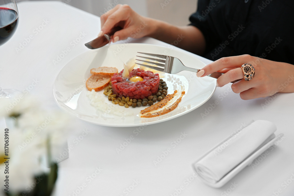 Woman eating beef tartare in restaurant