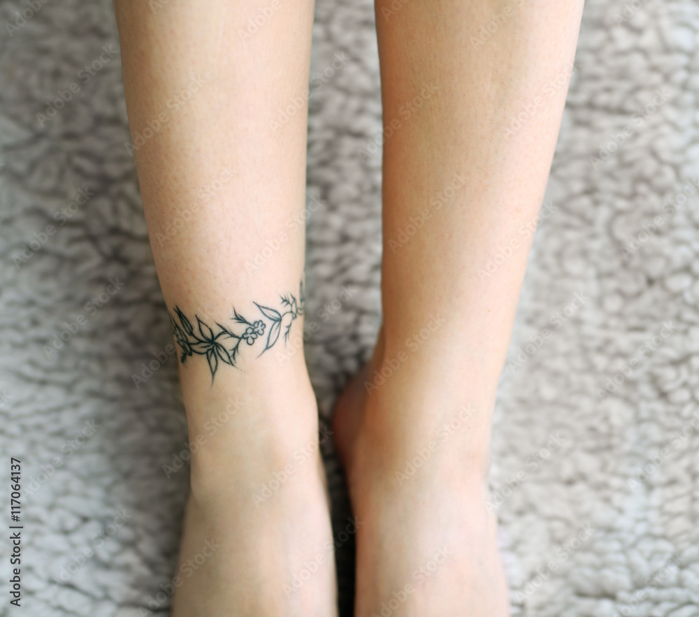 Female feet with tattoo on carpet