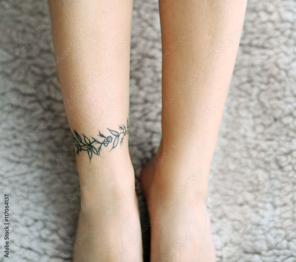Female feet with tattoo on carpet Female feet with tattoo on carpet