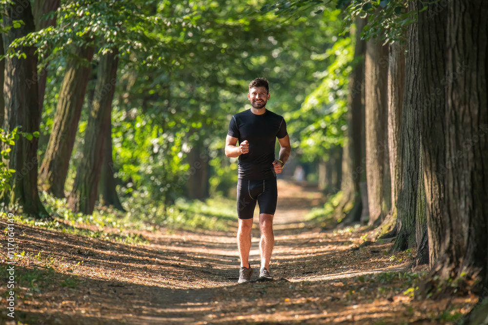 The athletic man run on the beautiful park alley