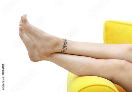 Female feet with tattoo on light background