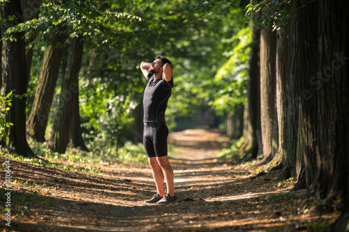 The sportsman do exercise on the beautiful park alley