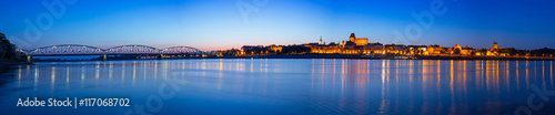 Panorama of Torun at night reflected in Vistula river, Poland
