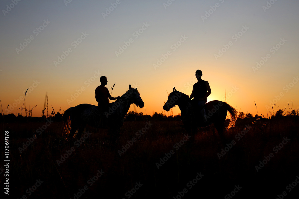 Riders silhouette on horseback at sunset