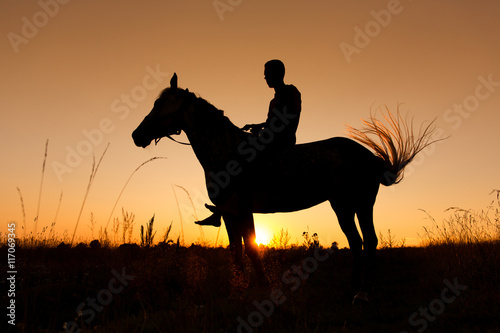 A rider silhouette on horseback at sunset