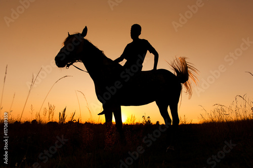 A rider silhouette on horseback at sunset