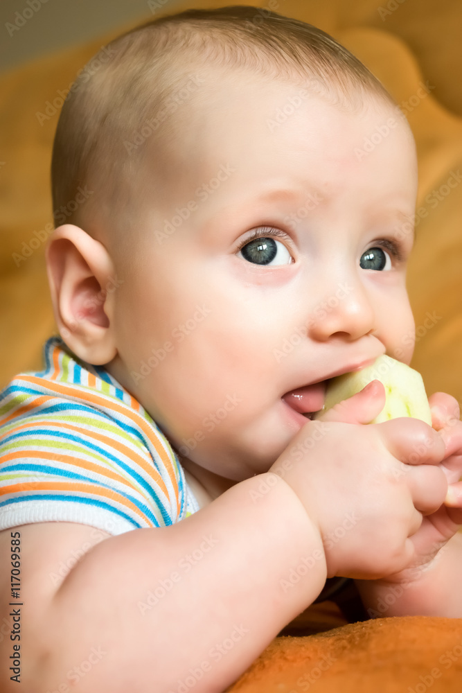 A portrait of an adorable child eating a first solid food - an apple