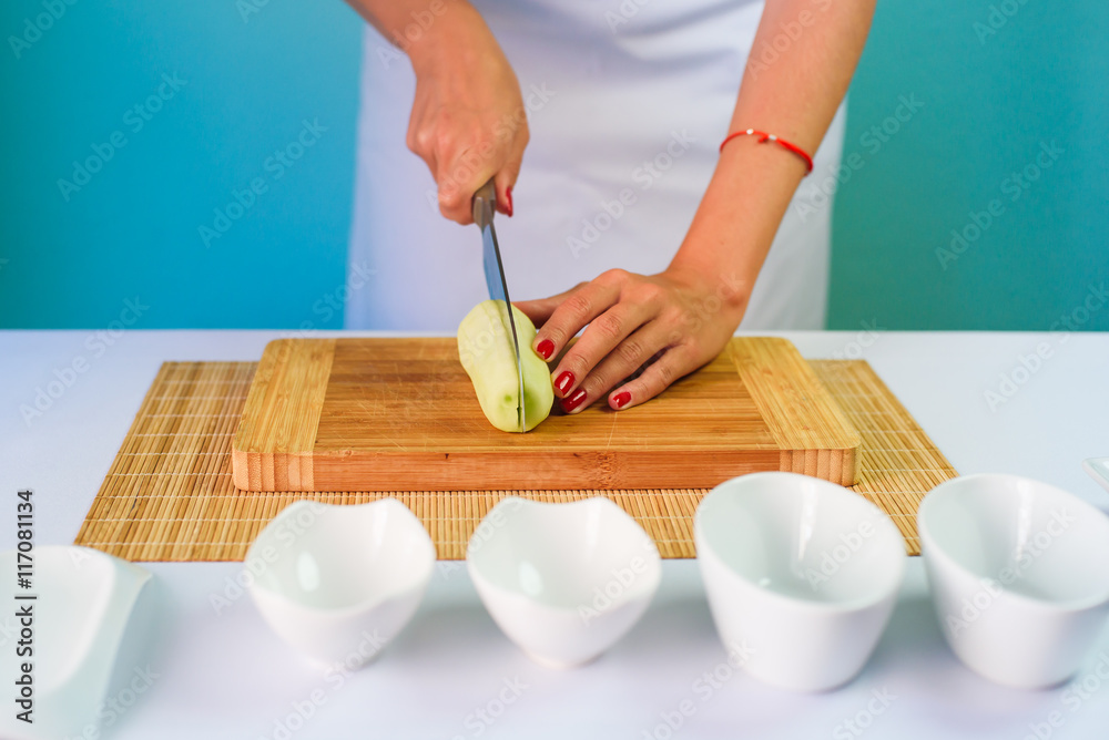 Close up picture of young lady's hands cutting cucumber Close up picture of young lady's hands cutting cucumber