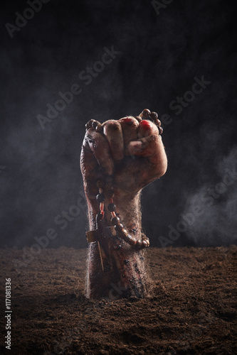 Human hand in blood and dirt with rosary