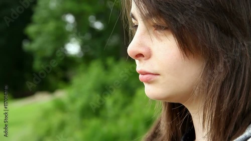 Young adult or late teens woman seated in park with a slightly worried look on her face.