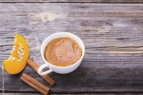 Quick meal breakfast snack in the microwave. Fragrant homemade pumpkin pie fall for five minutes in the cup portions with whipped cream and cinnamon on a wooden background